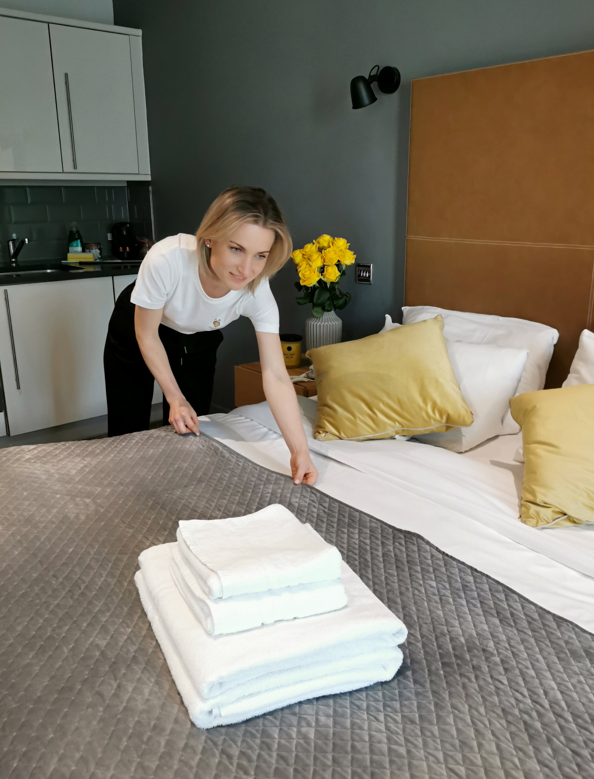 A Diamond Cleaning Expert team member making a bed with fresh linen and folded towels